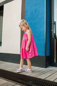 Full length portrait of young woman standing against building