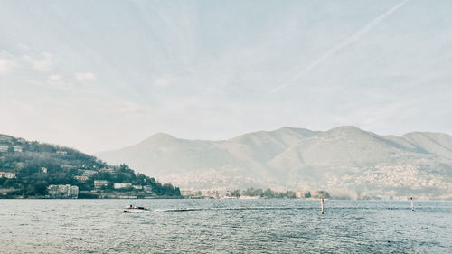 Scenic view of sea by mountains against sky