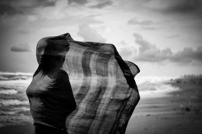 Rear view of man standing at beach against sky