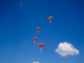 Low angle view of balloons flying against blue sky