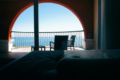 Low section of woman resting on bed by balcony against sea