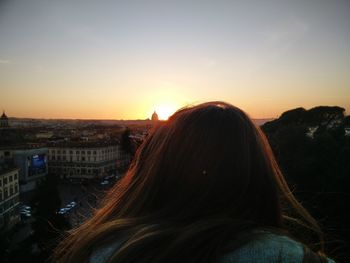 Rear view of woman against sunset sky