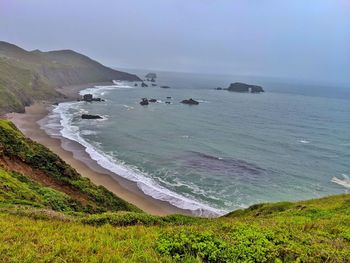 Scenic view of sea and curved ocean shoreline against sky