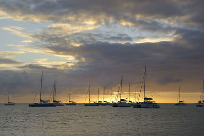 Sailboats sailing on sea against sky during sunset