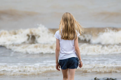 Rear view of girl standing at beach