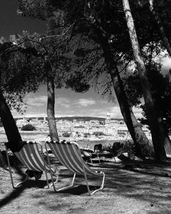 Empty chairs and tables at beach against sky