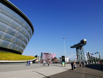 People in city against clear blue sky