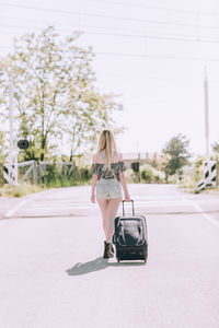 Full length of woman with luggage walking on road