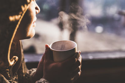 Cropped image of woman having drink during sunset