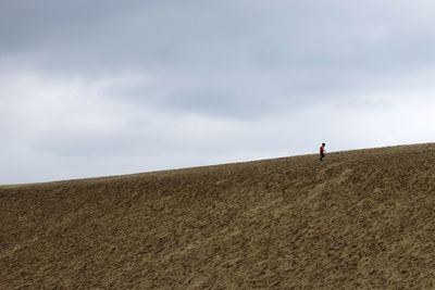 Man on arid landscape against sky