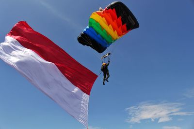 Low angle view of person paragliding against sky