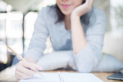 Midsection of woman writing on paper