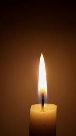 Close-up of lit candle against dark background
