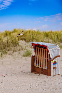 Hooded beach chairs on field against sky