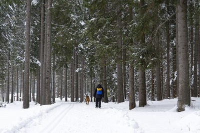 Rear view of person walking on snow covered field