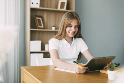 The girl studies at home with a digital tablet and does homework at school. 