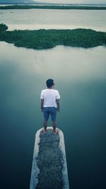 High angle rear view of man standing over lake