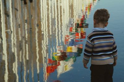 Boy looking at reflection of flags in river