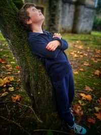 Full length of teenage boy on tree trunk during autumn