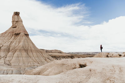 Man standing on rock formation against sky