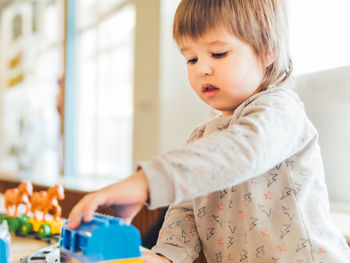 Toddler plays with colorful toy blocks. little boy stares on toy constructor. kindergarten