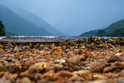 Stony shore of loch low level of land against sky