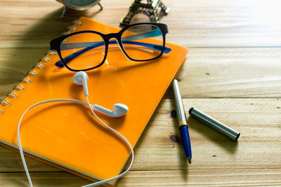 Close-up of eyeglasses with diary and alarm clock on table