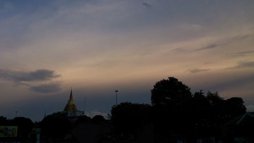 Silhouette trees and buildings against sky at dusk