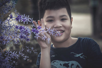 Portrait of smiling boy holding purple flowering plant