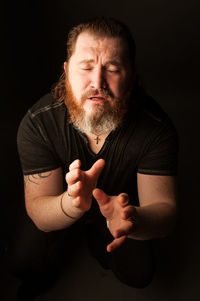 Portrait of man standing against black background