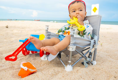 Boy sitting on chair at beach