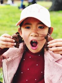 Close-up portrait of shocked girl holding cookies