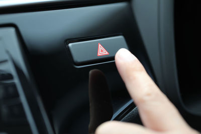 Cropped hand touching button in car