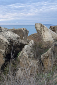 Rock formations on shore against sky