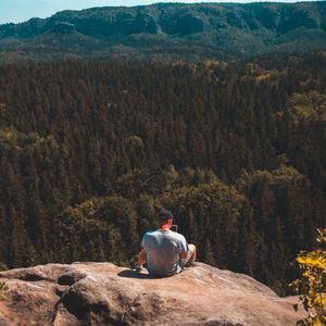 Rear view of man sitting on rock