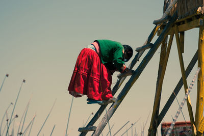 Low angle view of men working against clear sky