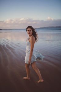 Portrait of smiling young woman standing on beach