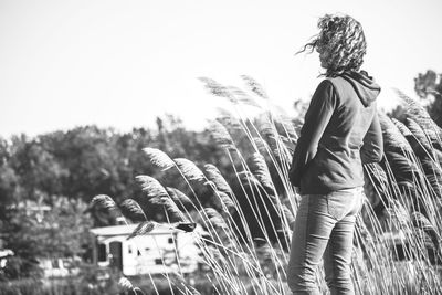 Rear view of woman standing by plants against sky