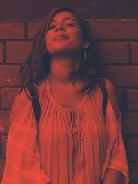 Portrait of a smiling young woman standing against wall