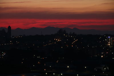 Illuminated cityscape against sky at sunset