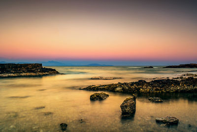 View of calm sea against clear sky at sunset