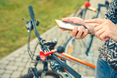 Midsection of person holding bicycle on mobile phone