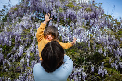 Rear view of woman standing against trees with child watching her