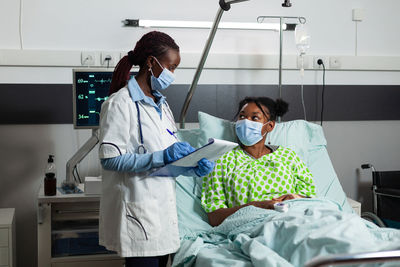 Female doctor wearing mask examining patient in hospital
