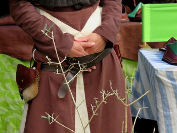 Midsection of person standing with hands in pocket during medieval fair