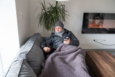 A woman with warm winter clothes at home on the sofa