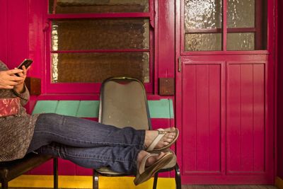 Low section of man sitting on door