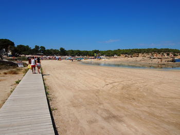 People on beach against clear blue sky
