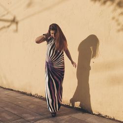 Portrait of young woman standing against wall