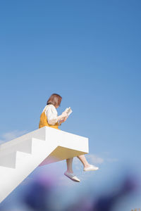 Asian woman relax and reading on white stair in flower garden on springtime vacation